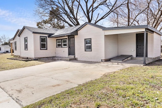 view of front of property with a shingled roof, concrete driveway, and a front lawn