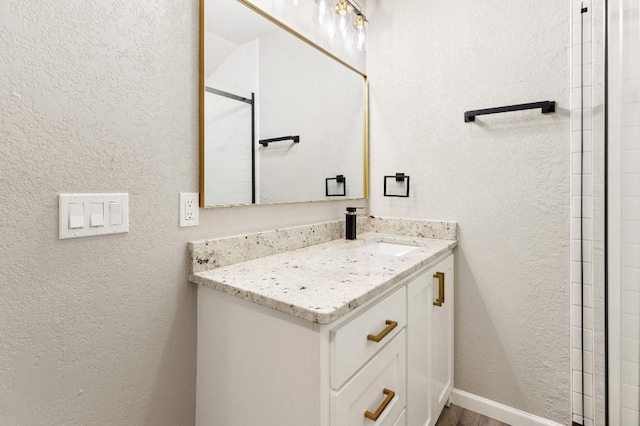 bathroom with vanity, baseboards, and a textured wall