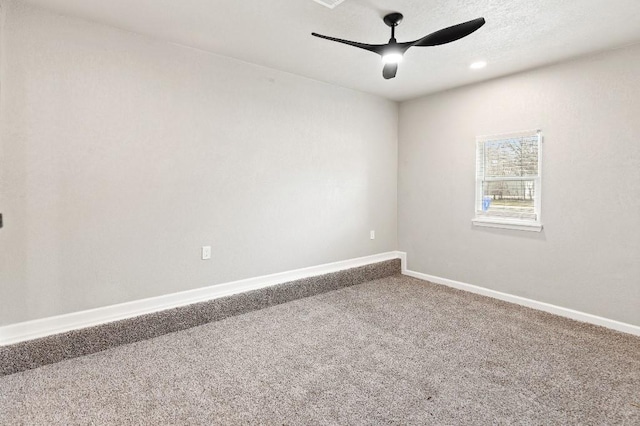 carpeted spare room featuring ceiling fan and baseboards