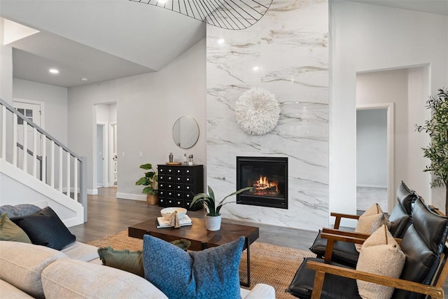 living room featuring stairs, wood finished floors, a premium fireplace, baseboards, and recessed lighting
