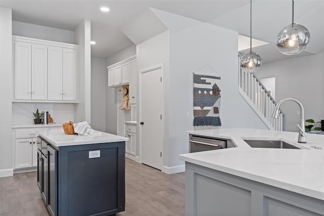 kitchen featuring white cabinetry, decorative light fixtures, a center island, a sink, and dishwasher