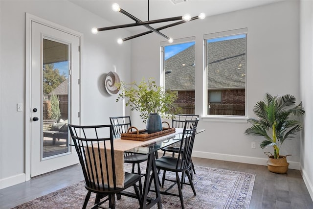 dining area with a notable chandelier, baseboards, a healthy amount of sunlight, and wood finished floors