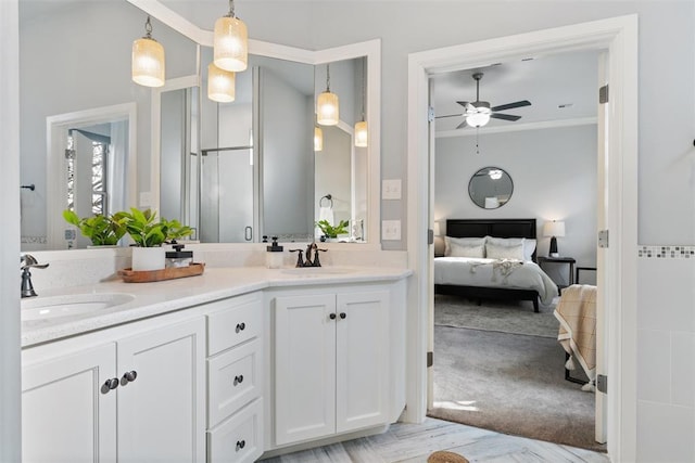 ensuite bathroom featuring double vanity, connected bathroom, a sink, and a ceiling fan
