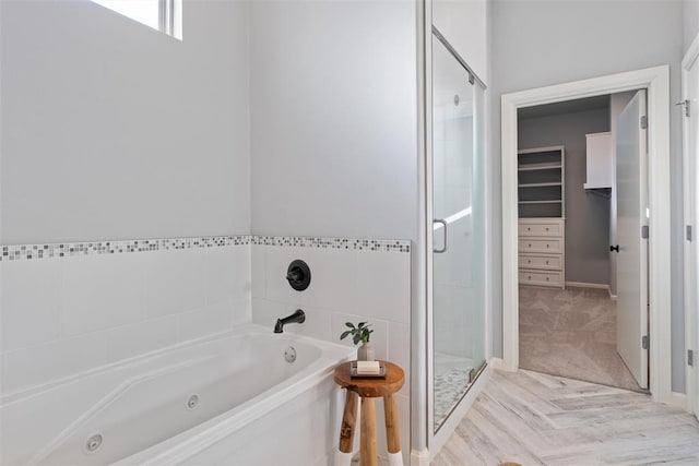 full bath featuring a tub with jets, a stall shower, and a spacious closet
