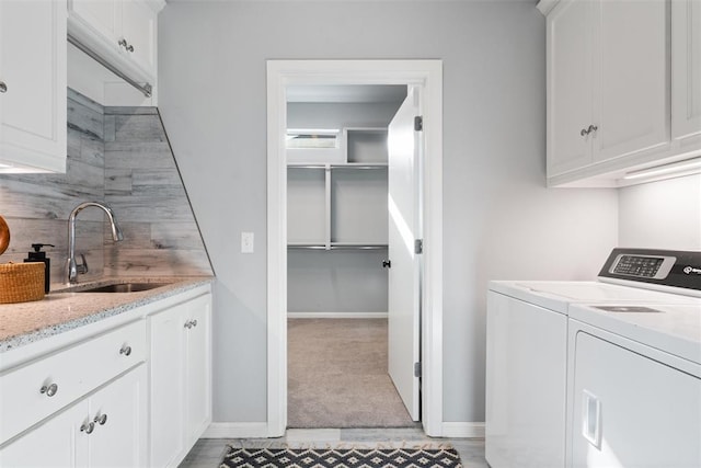 laundry room with a sink, separate washer and dryer, baseboards, light colored carpet, and cabinet space
