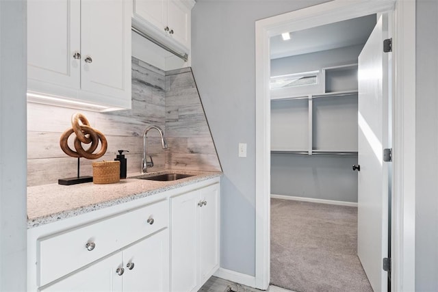 bar with baseboards, a sink, tasteful backsplash, and light colored carpet
