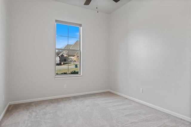carpeted spare room featuring a ceiling fan and baseboards