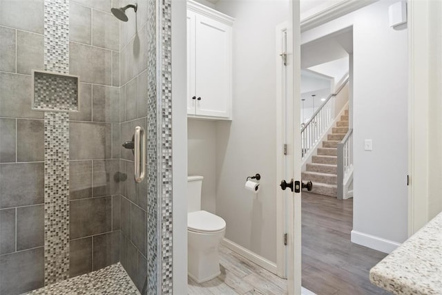 full bathroom featuring a stall shower, baseboards, wood finished floors, and toilet