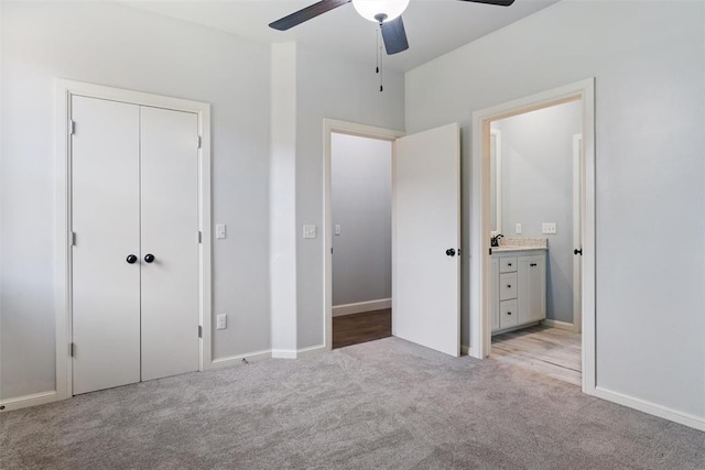 unfurnished bedroom featuring ensuite bathroom, a closet, baseboards, ceiling fan, and light colored carpet
