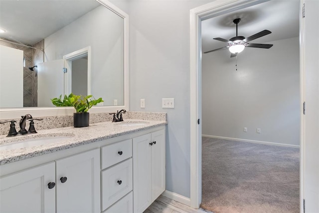 bathroom featuring double vanity, ceiling fan, a sink, and baseboards
