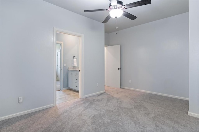 unfurnished bedroom featuring ensuite bath, baseboards, light colored carpet, and ceiling fan