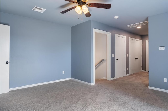 carpeted spare room with a ceiling fan, baseboards, and visible vents