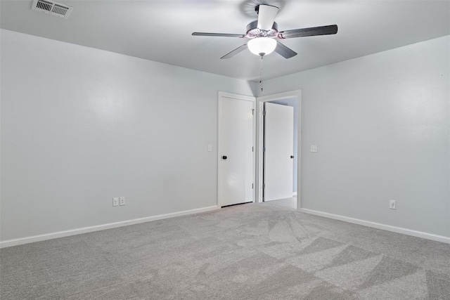 carpeted spare room featuring baseboards, ceiling fan, and visible vents