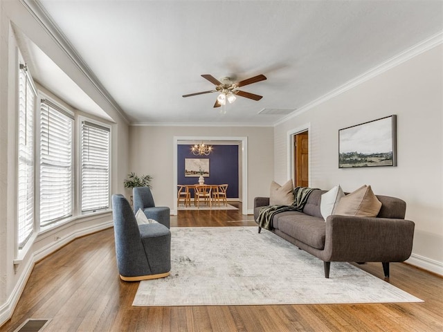 living room featuring ornamental molding, wood finished floors, visible vents, and baseboards