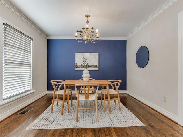 dining area with a chandelier, ornamental molding, wood finished floors, and visible vents