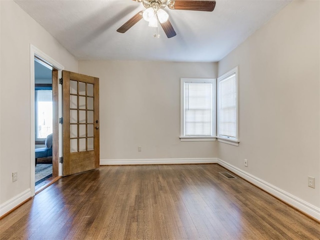 spare room featuring a wealth of natural light, baseboards, and wood finished floors