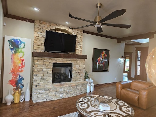 living room with a stone fireplace, wood finished floors, and crown molding