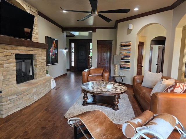 living room featuring crown molding, baseboards, wood finished floors, and a stone fireplace