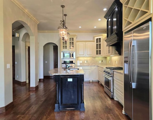 kitchen with arched walkways, decorative backsplash, appliances with stainless steel finishes, glass insert cabinets, and a sink