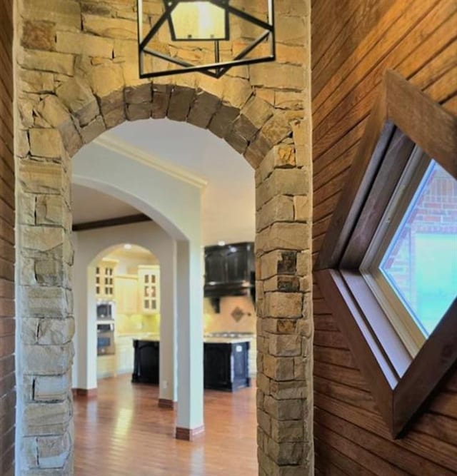 interior space featuring crown molding, arched walkways, and wood finished floors