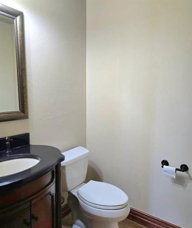 half bath with vanity, toilet, and baseboards