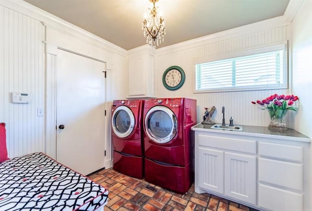 laundry room with brick floor, washing machine and dryer, a notable chandelier, a sink, and cabinet space