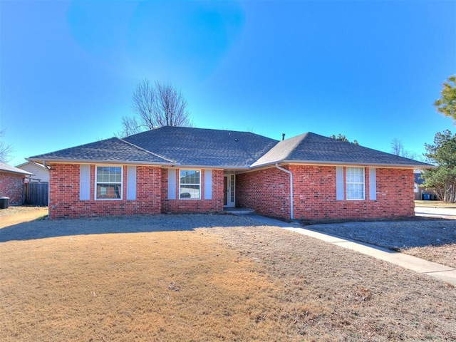 ranch-style home with brick siding, a shingled roof, and cooling unit