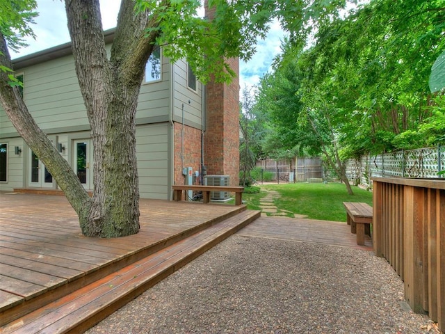 deck featuring fence private yard, cooling unit, and a lawn