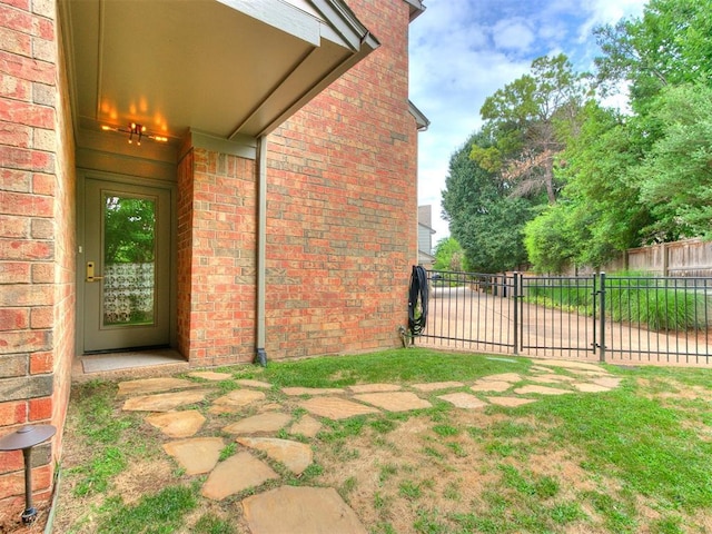 exterior space with a yard, brick siding, and fence