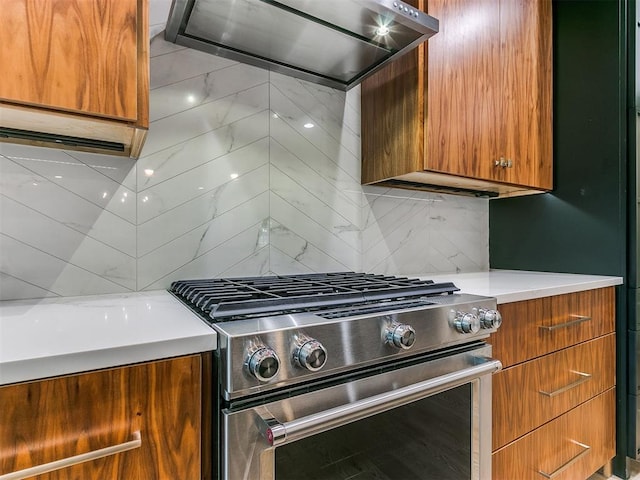 kitchen featuring tasteful backsplash, ventilation hood, light countertops, brown cabinets, and high end stainless steel range oven