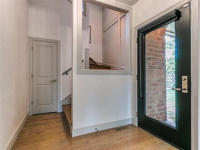 doorway to outside featuring baseboards, visible vents, and wood finished floors