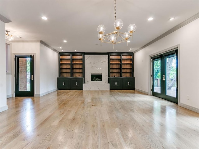 unfurnished living room featuring baseboards, built in features, wood finished floors, and ornamental molding