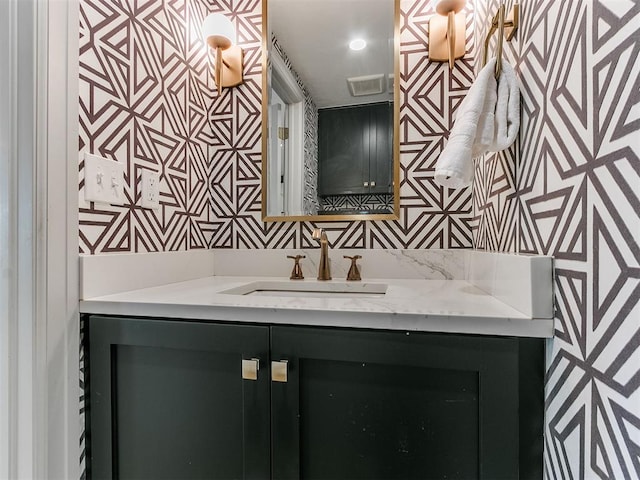 bathroom featuring visible vents, wallpapered walls, and vanity