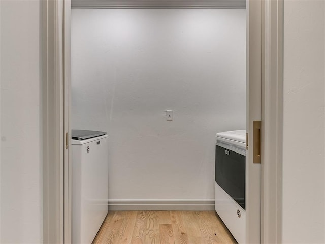 laundry area featuring laundry area, baseboards, washer and clothes dryer, and light wood-style floors