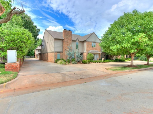 view of front facade featuring a chimney, concrete driveway, and brick siding