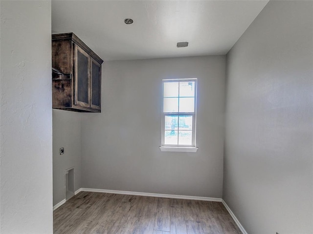 empty room with wood finished floors, visible vents, and baseboards