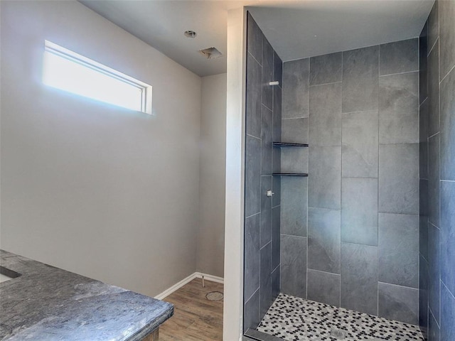 bathroom featuring tiled shower, wood finished floors, and baseboards