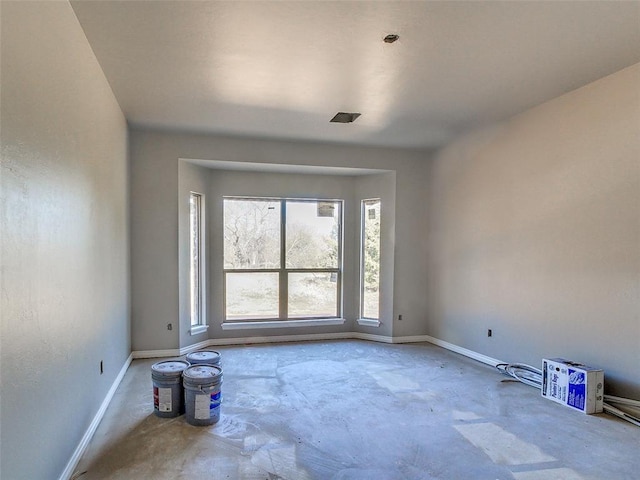 unfurnished room with baseboards and unfinished concrete floors