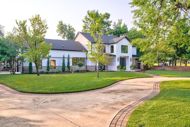 view of front of house with concrete driveway, a front lawn, and stucco siding