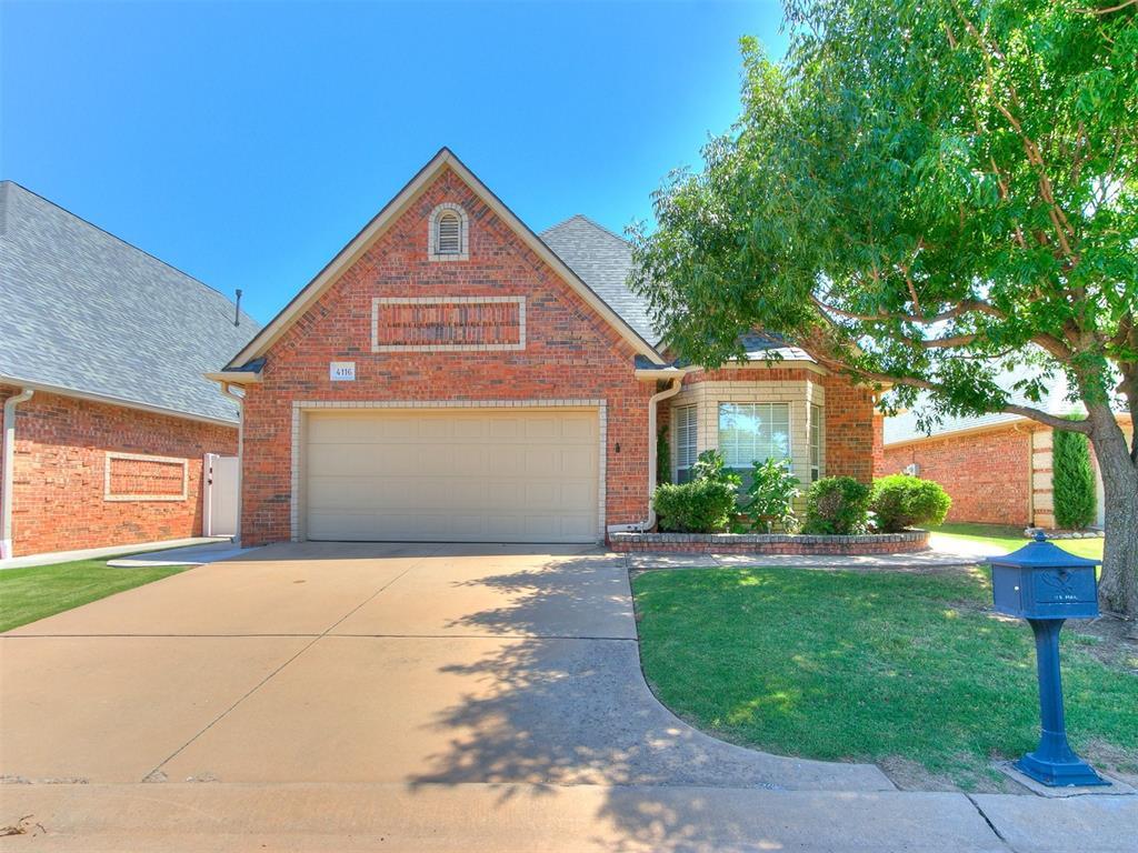 traditional-style home with brick siding, roof with shingles, concrete driveway, a front yard, and a garage