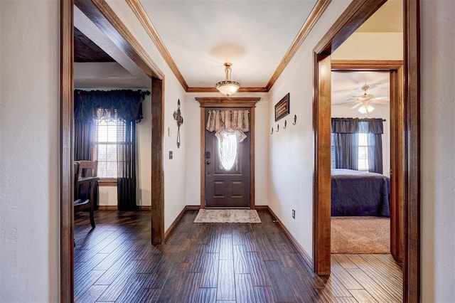 foyer entrance with ornamental molding, dark wood-type flooring, and baseboards