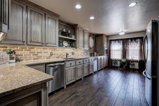 kitchen featuring tasteful backsplash, dishwasher, dark wood-style floors, freestanding refrigerator, and a sink