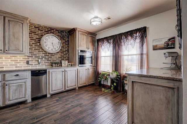 kitchen featuring visible vents, light stone counters, dark wood finished floors, and stainless steel oven