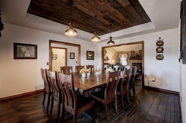 dining area with dark wood-type flooring, a tray ceiling, wooden ceiling, and baseboards