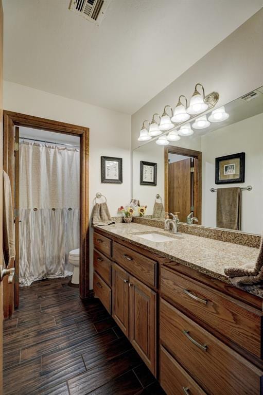 bathroom with visible vents, vanity, toilet, and wood finished floors