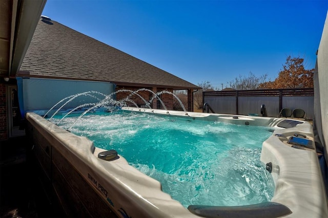 view of swimming pool with fence and a hot tub