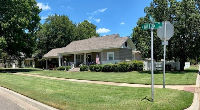 view of front of house featuring covered porch, a front lawn, and fence