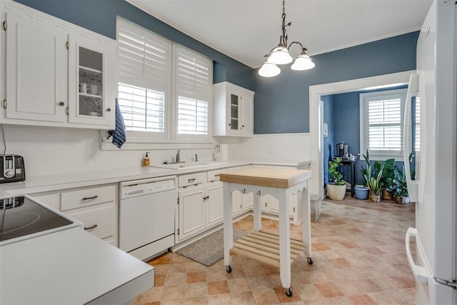 kitchen featuring white appliances, a sink, decorative light fixtures, and white cabinets