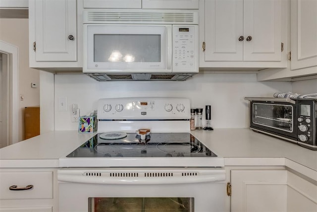 kitchen with white appliances, a toaster, white cabinetry, and light countertops