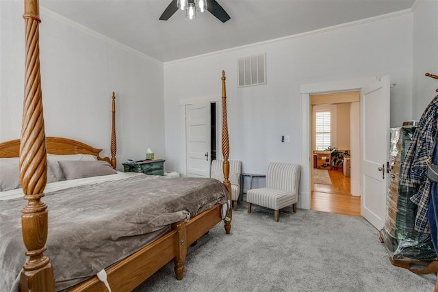 carpeted bedroom with ceiling fan, visible vents, and crown molding